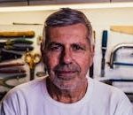 Portrait of a senior man with tools in the background, exuding confidence.